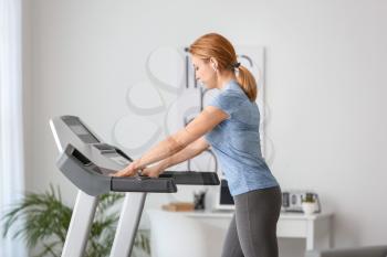 Sporty woman training on treadmill at home�