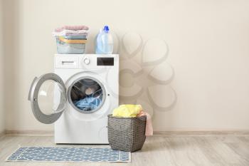 Washing machine and basket with laundry near light wall�