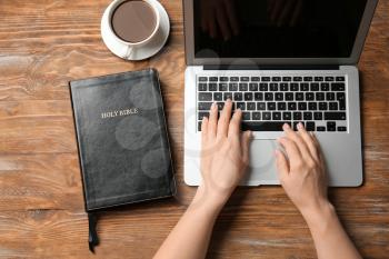 Religious woman working on laptop at table�