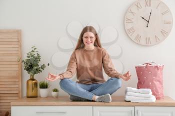 Young woman meditating while doing laundry at home�