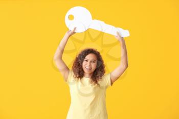 Young woman with big paper key on color background�