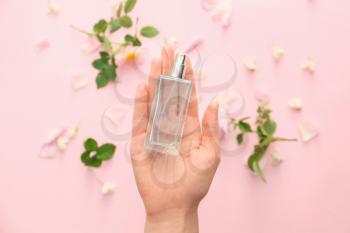 Female hand with floral perfume on color background�