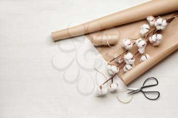 Beautiful cotton flowers, wrapping paper, thread and scissors on white background�