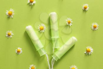 Menstrual tampons with chamomile flowers on color background�