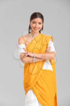 Beautiful young Indian woman on grey background�