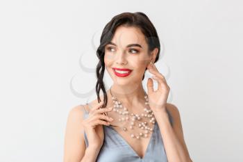 Beautiful young woman wearing stylish jewelry on light background�