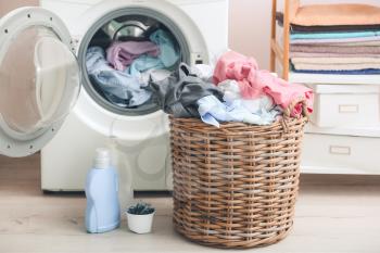 Washing machine and basket with dirty clothes in home laundry room�