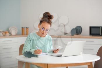 Young woman using tablet computer and laptop for online learning at home�
