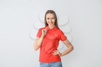 Beautiful young woman in stylish polo shirt on light background�