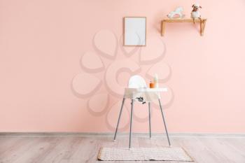 Modern interior with baby highchair on color background�