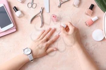 Woman doing manicure on color background�