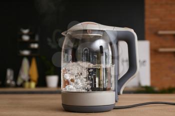 Electric kettle with boiling water on kitchen table�