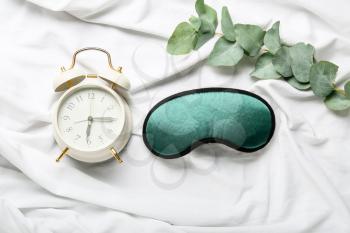 Sleep mask and alarm clock on light background�