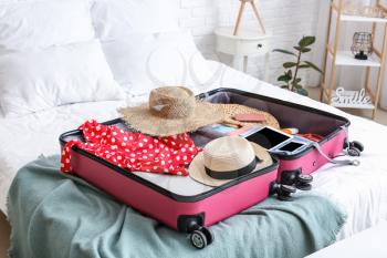 Packed suitcase with beach accessories on bed. Travel concept�
