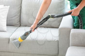 Dry cleaner's employee removing dirt from sofa in house�