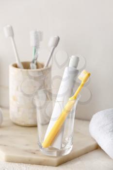 Holder with toothbrushes and toothpaste on table in bathroom�