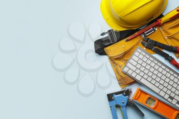 Construction tools and computer keyboard on color background�
