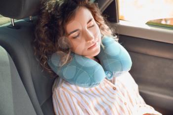 Beautiful young woman with travel pillow sleeping in car�
