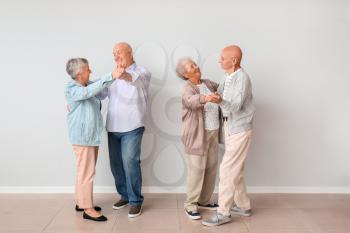 Senior couples dancing near light wall�