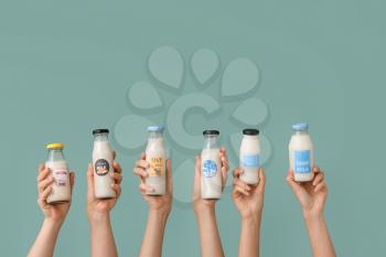 Female hands with bottles of vegan milk on color background�