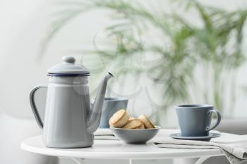 Teapot and cup with tea on table in room�