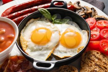 Traditional English breakfast with fried eggs in plate, closeup�