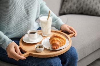 Woman holding tray with tasty breakfast in room�