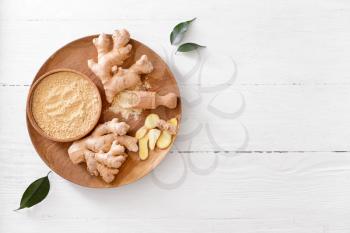 Bowl with ginger powder on light wooden background�