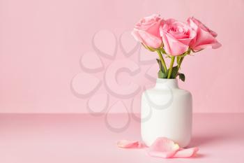 Beautiful pink roses in vase on color background�