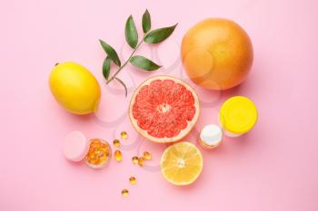 Bottles with vitamin C pills and citrus fruits on color background�