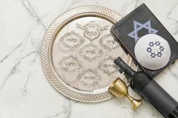 Passover Seder plate with wine, Jewish cap and Torah on white background�