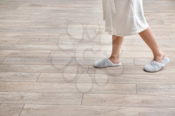 Woman in slippers walking on new laminate flooring at home�