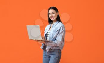 Young woman with laptop on color background�