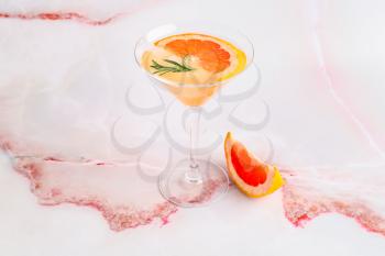 Glass of tasty grapefruit cocktail on light background�