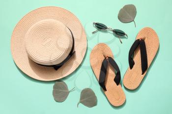 Stylish beach hat with sunglasses and flip-flops on color background�