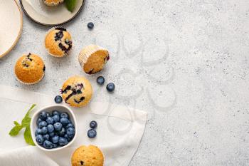 Composition with tasty blueberry muffins and berries on light background�