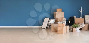 Carton boxes and interior items prepared for moving into new house near color wall�