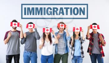Group of students with Canadian flags and word IMMIGRATION on light background�