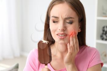 Young woman with sensitive teeth and cold ice-cream at home�