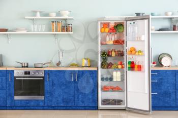 Open big fridge with products in interior of kitchen�