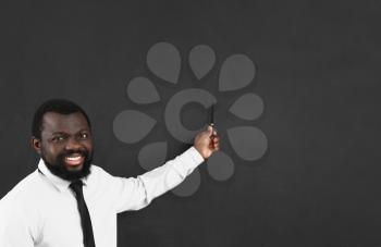 African-American teacher pointing at something on blackboard in classroom�