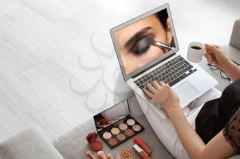 Female makeup artist with laptop at home�