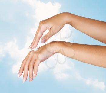 Royalty Free Photo of a Woman's Hands With Cream Against a Sky