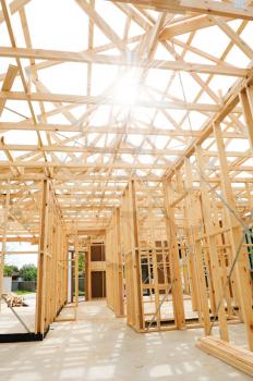 
New residential construction home framing against a sunny sky.