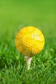 yellow golf ball on a tee over green grass outdoors