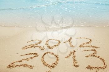 digits  2012 and 2013 on the sand seashore - concept of new year and passing of time