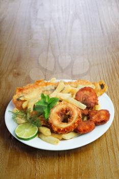Seafood dish with crumbed fish,calamari,prawn and potato chips on vintage table 