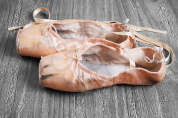 Old used  ballet pointe shoes on vintage wooden background
