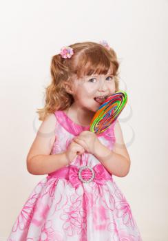 Portrait of cute little girl with big colorful lollipop  on a light background