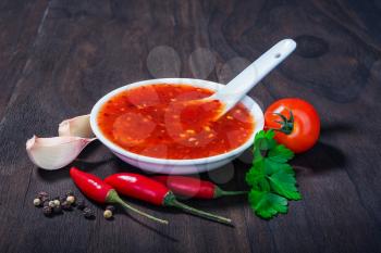 red hot sweet chilli sauce over old wooden background
